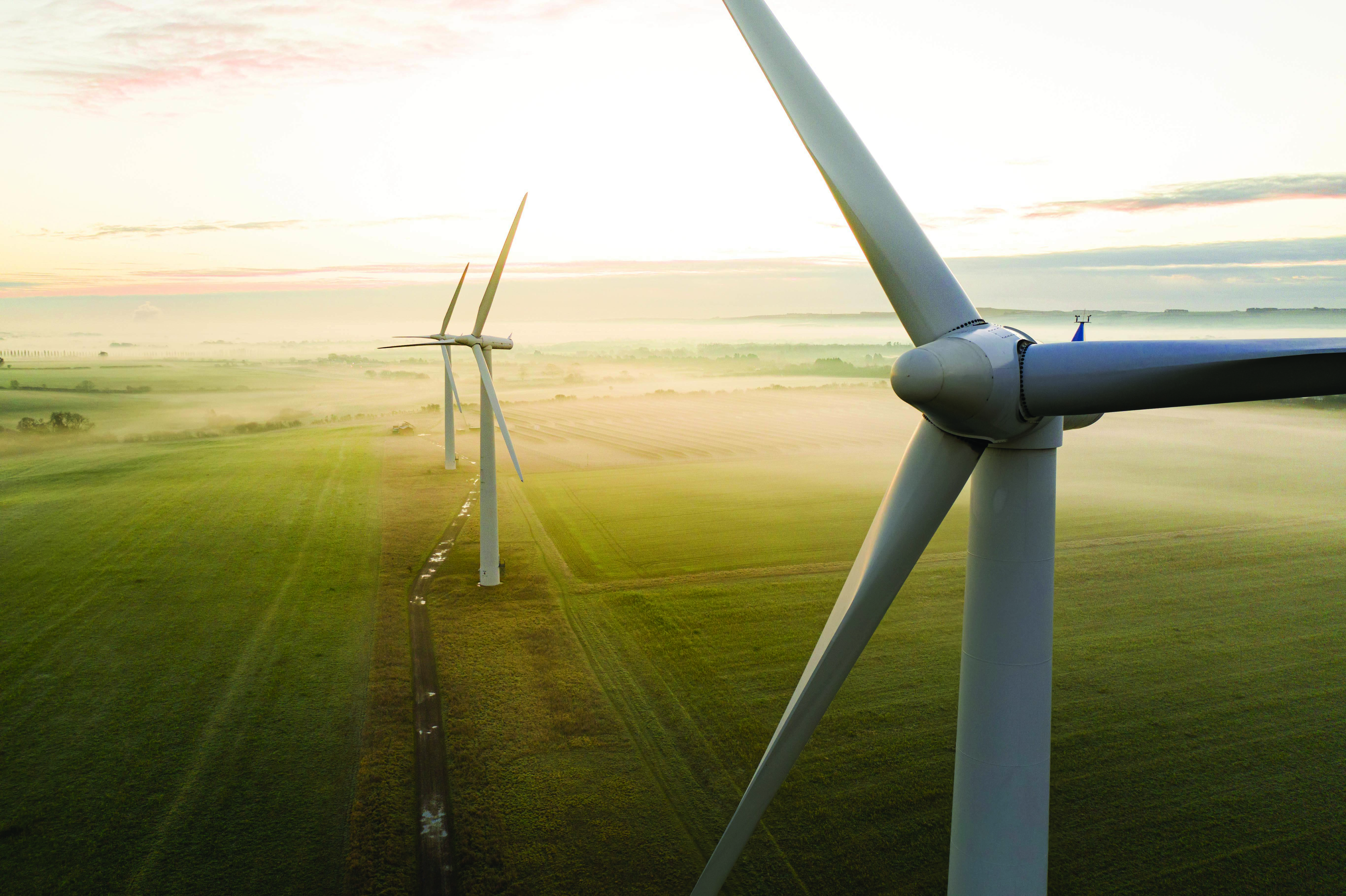 image of windfarm up close with two in the distance on a sunny morning