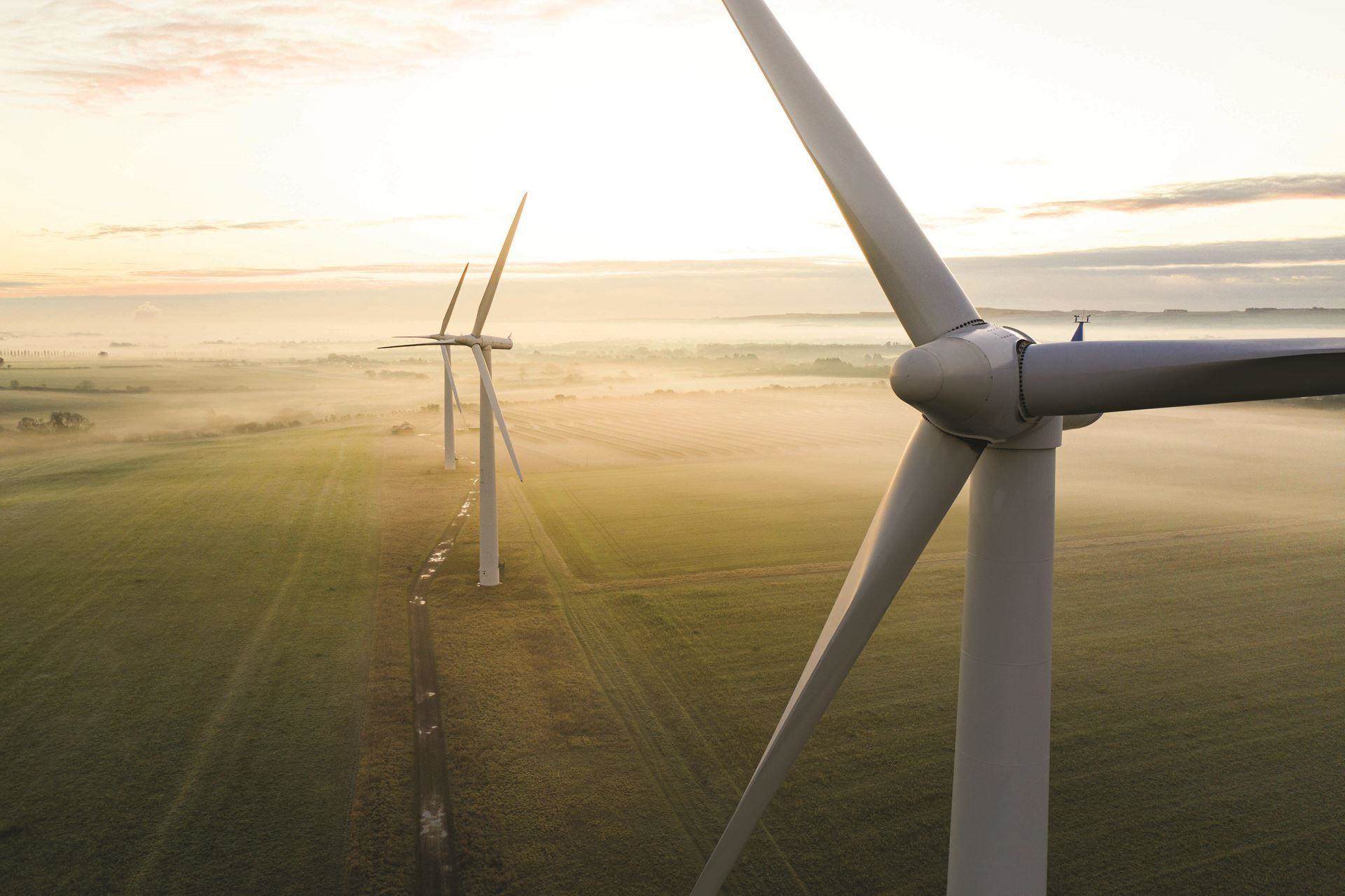 image of windfarm up close with two in the distance on a sunny morning