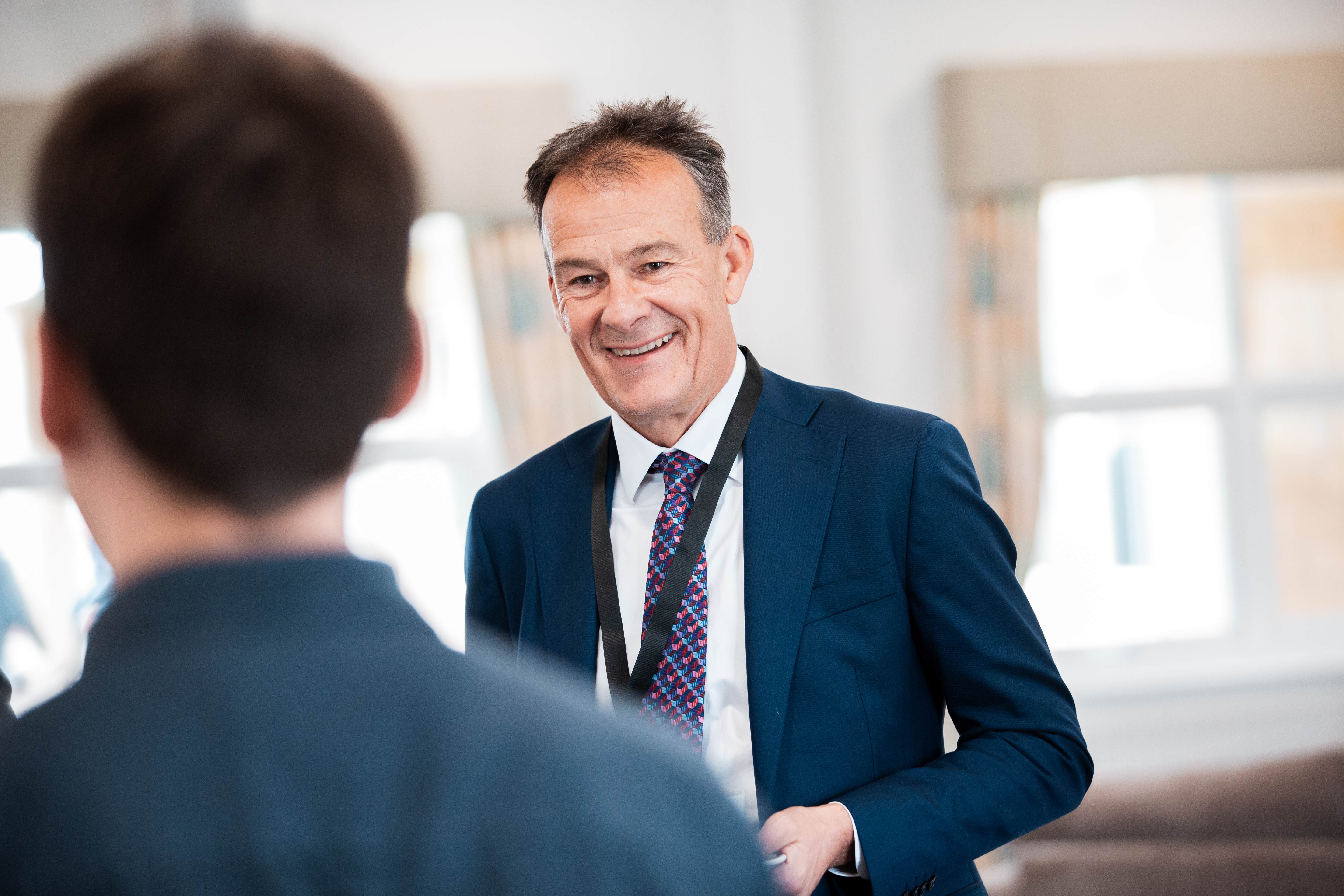 man smiling at someone in corporate setting wearing lanyard