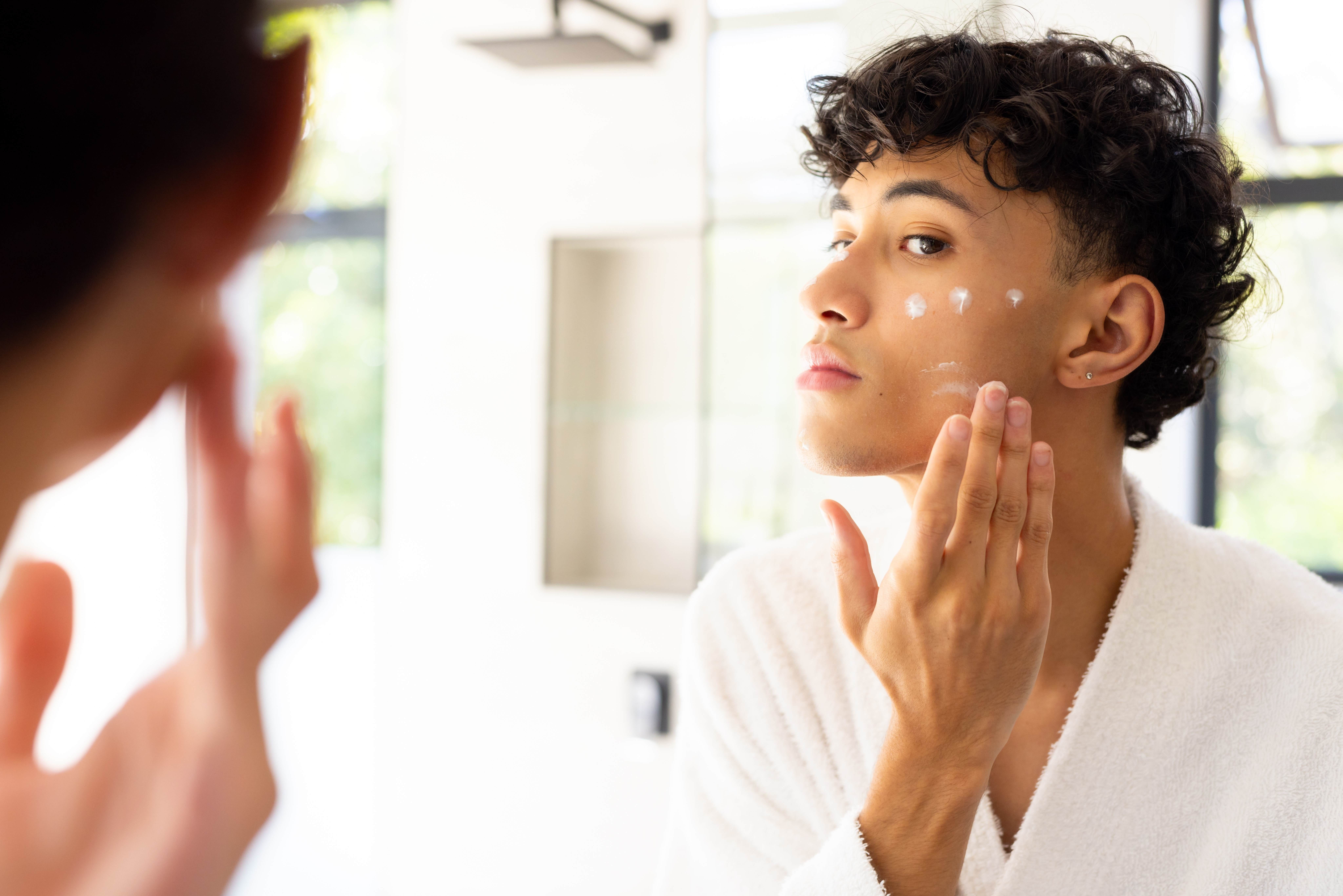 male applying skincare with white formulation