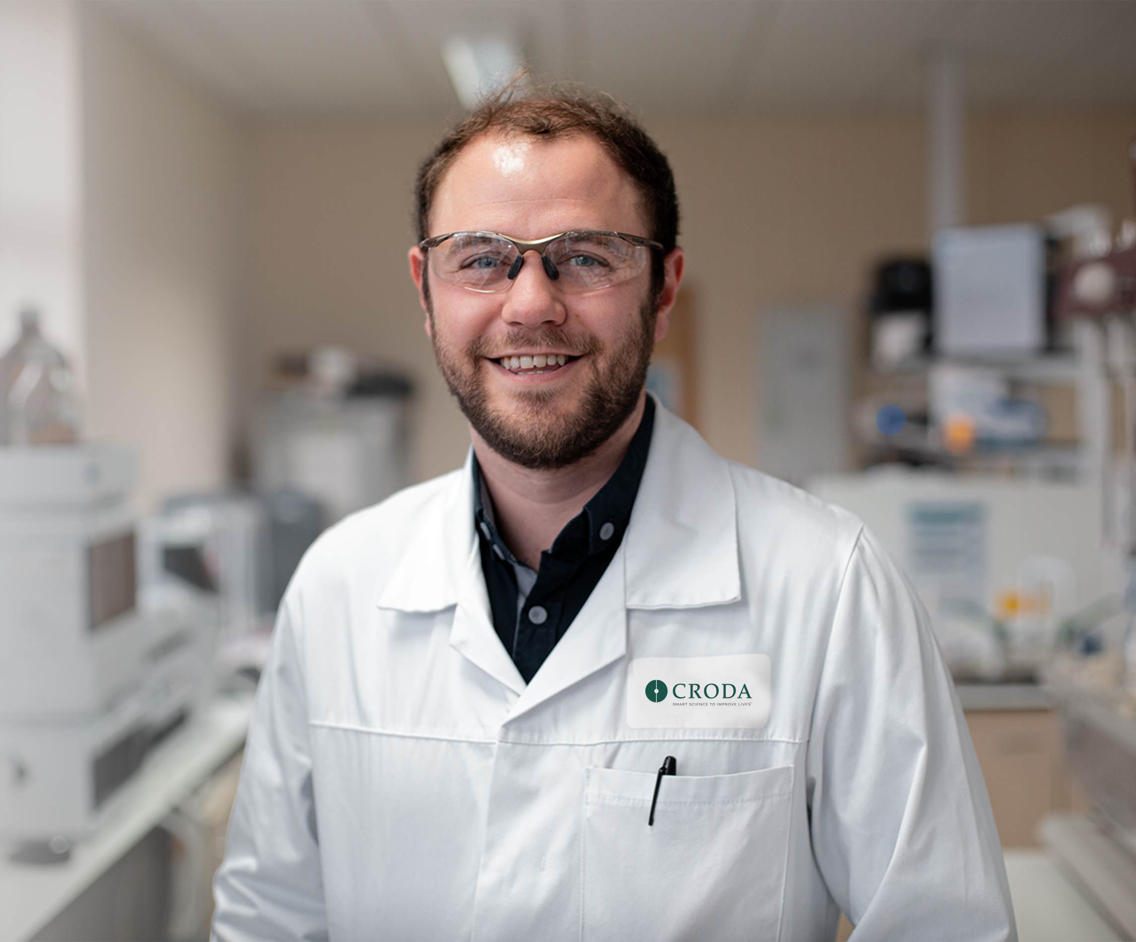 scientist stood in lab smiling wearing safety equipment