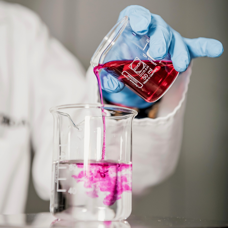 Scientist pouring liquid from one beaker to another