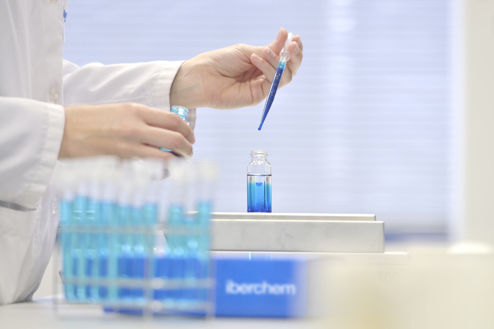 Scientist with a beaker and pipette working with a blue liquid