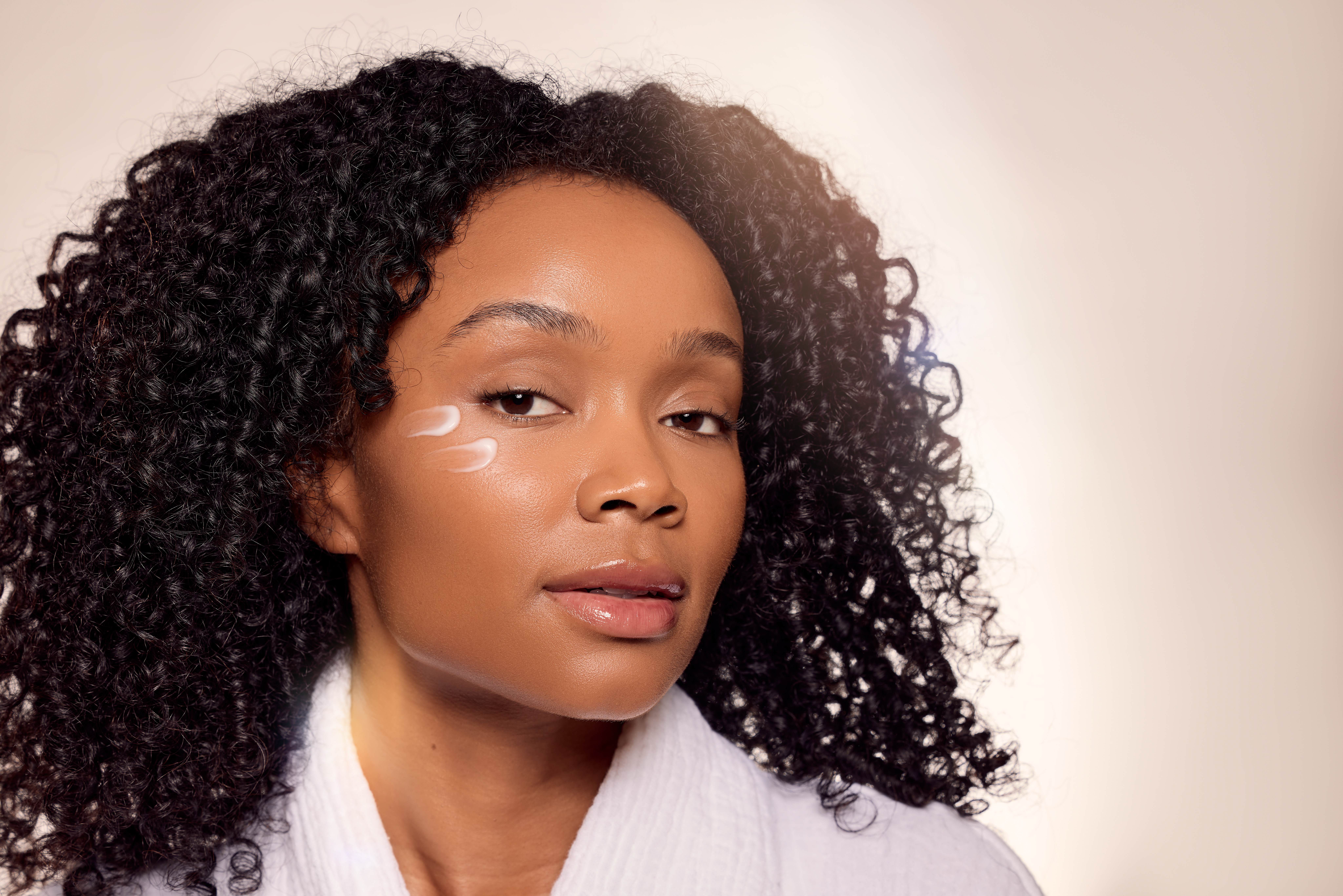 Lady with curly hair and cream on her face
