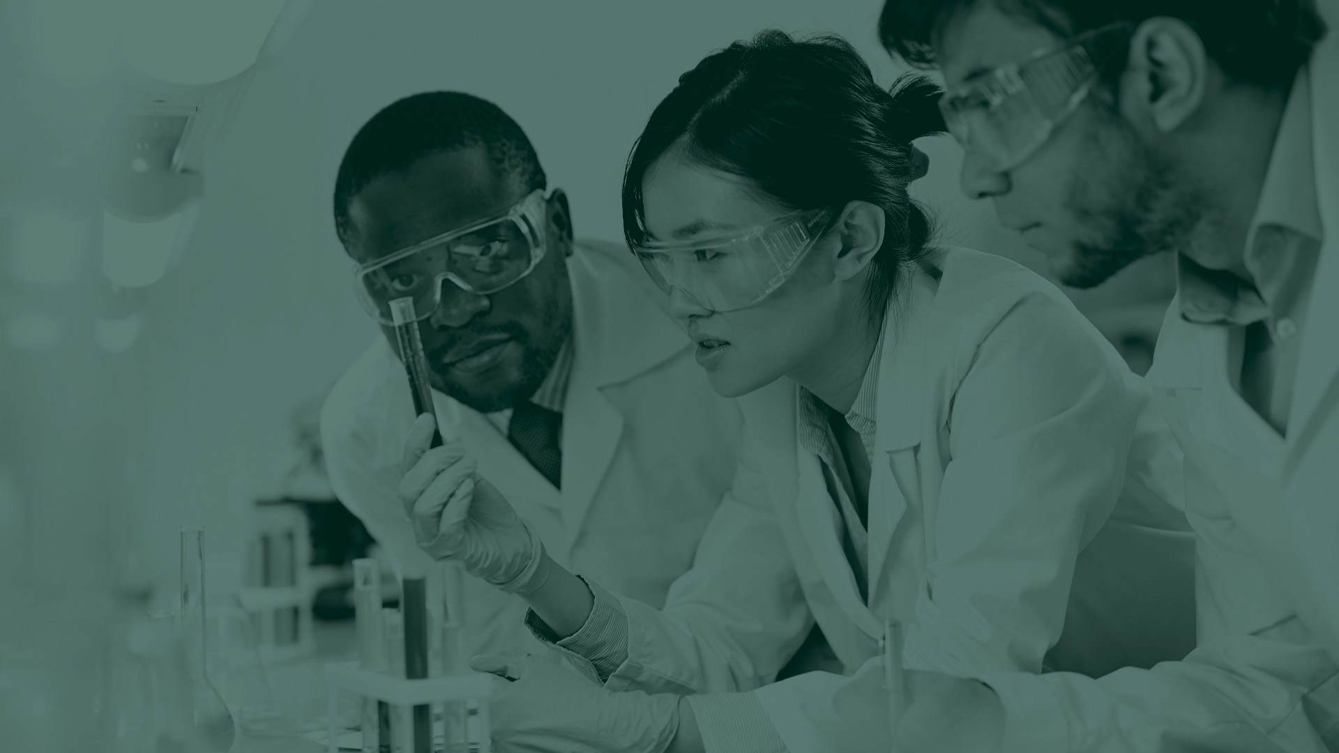 Green tone image of three scientists in a lab looking closely at an experiment
