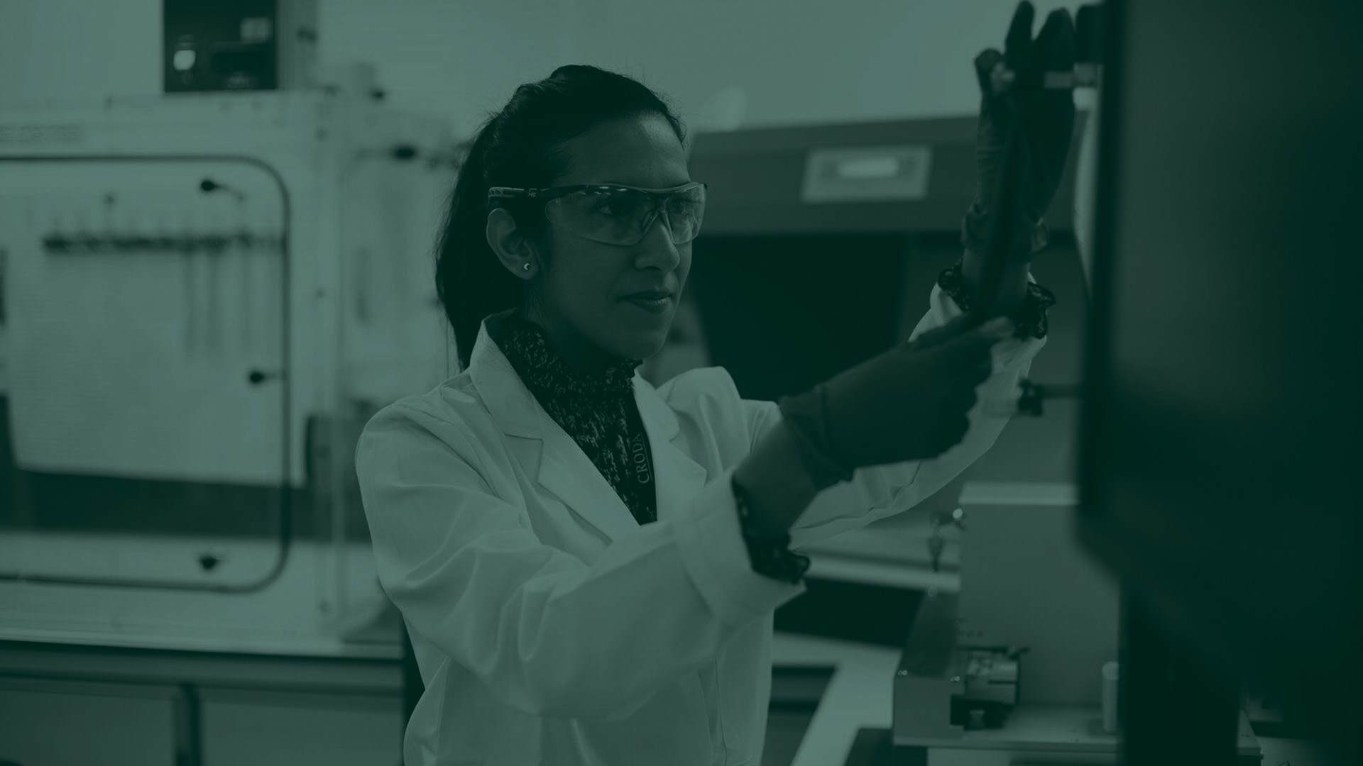 Green tone image of a lady in a lab looking at a machine
